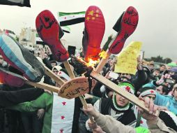 Un manifestante sirio quema zapatos pintados con banderas rusas y chinas, y con los nombres del presidente sirio. REUTERS  /