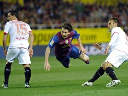 Messi cae ante dos defensores del Sevilla durante el partido. AFP  /