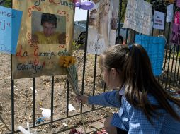 Una niña coloca flores frente a la foto del joven asesinado. AFP  /