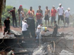 Reclusos hondureños lanzan desde el tejado agua para poder sofocar el incendio en el interior del Centro Penal de San Pedro Sula. EFE  /