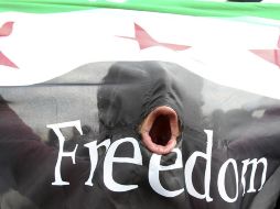 Un manifestante sostiene una bandera siria con la leyenda Libertad. REUTERS  /