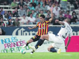 Cesar Valdovinos, de la UdeG, trata de disparar ante la llegada de Juan Carlos Arellano, defensor del Irapuato.  /
