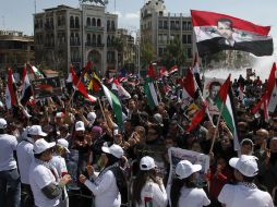 Varios sirios y palestinos ondean banderas y muestran fotos del presidente sirio Bashar al Assad. EFE  /