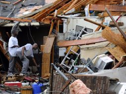 Dos hombres limpian escombros en una casa afectada  tras el paso de un tornado en Lancaster. EFE  /