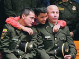 Carlos abraza a su padre, el policía Carlos José Duarte (izquierda) y a Wilson Rojas Medina durante una ceremonia religiosa. EFE  /