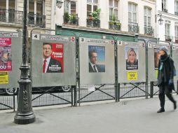 INUNDAN LAS CALLES.- Una mujer camina junto a los pósters oficiales de los 10 candidatos a la Presidencia, en París. REUTERS  /