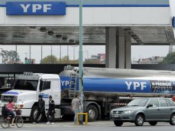 Varias personas pasan hoy jueves frente a un camión cisterna de la petrolera YPF, en Buenos Aires. EFE  /