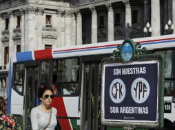 Una mujer camina junto a un fiche de apoyo a la expropiación de la petrolera YPF. EFE  /