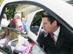 Aristóteles Sandoval charla con una mujer a la llegada de una de sus actividades proselitistas.  /