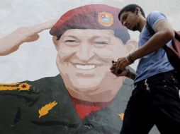 Un joven camina frente a un mural con la imagen de Hugo Chávez en Venezuela. AFP  /