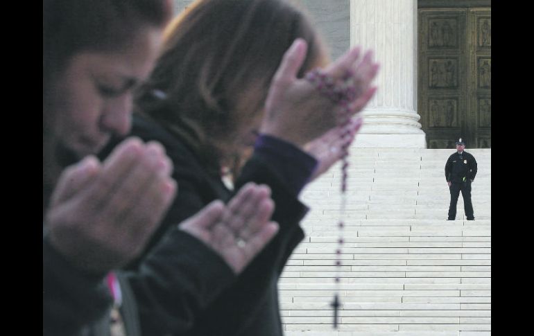Personas rezan afuera del Tribunal Supremo donde discuten la aplicación de la ley migratoria en Arizona. AFP  /