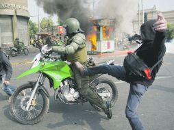 Los encapuchados golpean a un policía durante las protestas estudiantiles en Santiago. AFP  /