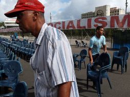 Dos hombres alinean sillas en la Plaza de la Revolución de La Habana antes del desfile por el día internacional del trabajo. EFE  /