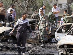 Soldados y civiles inspeccionan la zona de una de las explosiones. AFP  /