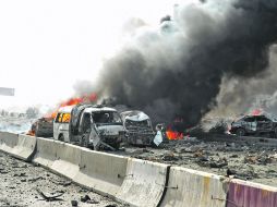 Varios automóviles arden en una carretera del barrio de al-Qazaz donde ocurrió uno de los dos ataques suicidas.AFP  /