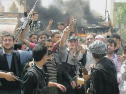 El Ejército Sirio Libre se manifiesta delante de un tanque incendiado, en Rasten, cerca de Homs. AFP  /