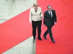 La reunión entre Merkel y Hollande (der.) se atrasó debido a que un rayo alcanzó el avión en el que viajaba el presidente francés. AFP  /
