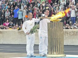 El levantador de pesas Pyrros Dimas y el gimnasta chino Li Ning encienden la Antorcha Olímpica para su traslado al Reino Unido.EFE  /