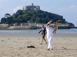 Johanna Dickinson saluda en su turno al portar la antorcha olímpica en su recorrido por el Reino Unido. AP  /
