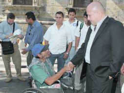 Enrique Alfaro saluda a una persona en silla de ruedas frente a Palacio de Gobierno.  /