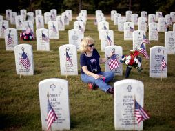 Una mujer acude a la tumba de su marido, muerto en acción, para celebrar el Memorial Day. AP  /
