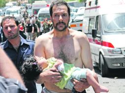 Un hombre sirio lleva a una niña herida cerca de las ambulancias de la Media Luna Roja tras un ataque. AP  /