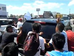 Imagen tomada de YouTube donde se observa a un contigente agrediendo la unidad en la que se transporta Enrique Peña Nieto en Tepeaca.  /