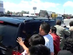 Imagen de YouTube en la que se observa a personas dando manoteos al vehículo que transportaba a Peña Nieto.  /