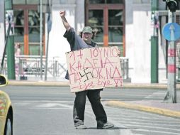 Un hombre sostiene una pancarta con la leyenda “17 de junio es el funeral del PASOK y Nueva Democracia”, en Atenas. AP  /