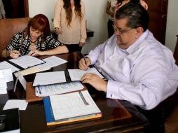 Firma con la directora del organismo cubano Patricia Rodríguez y el presidente municipal Francisco Ayón.  /