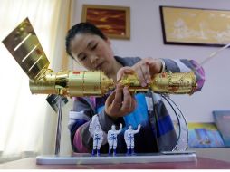 En una tienda de modelismo china, una empleada afina un modelo de la cápsula Shenzhou 9 acoplándose al módulo Tiangong I. REUTERS  /