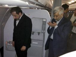 El negociador nuclear iraní Saeed Jalili (d) reza al interior del avión que los traslada a Moscú. EFE  /