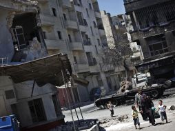 Una familia siria camina a través de un barrio bombardeado por el gobierno. AP  /