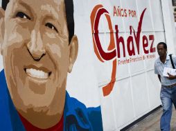 Un hombre camina frente a un muro con un retrato de Hugo Chávez. REUTERS  /