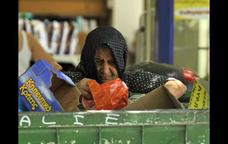 Una anciana griega busca comida entre la basura de un centro comercial en Tesalonia. AP  /