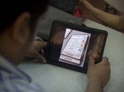 Un empleado en el recuento de IFE observa fotos en las que se documentan los paquetes recontados. AFP  /