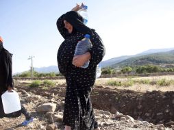 Refugiados sirios cargan agua en Hatay, uno de los ocho campos instalados en Turquía para quienes huyen del conflicto en su país. EFE  /