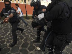 Policías escoltan al hombre que fue detenido después de amenazar contra manifestantes. REUTERS  /