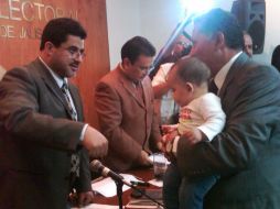 Cargando a su nieto, Arturo Zamora (d) recibió el documento del consejero presidente del IFE local, Matías Chiquito.  /