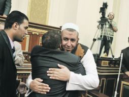 Miembros del parlamento egipcio se abrazan tras una breve sesión que contradice el fallo judicial de su disolución, en El Cairo. AP  /