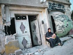 Una mujer sostiene a un niño frente a su casa destruida en Tremesh, donde el 12 de julio masacraron a por lo menos 200 personas. AFP  /