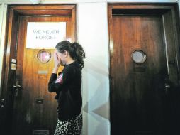 Una activista cubre su rostro mientras apunta un cartel  colocado en la puerta del apartamento de Laszlo Csatary. AFP  /