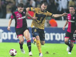 Leandro Cufré, Atlas, disputa el esférico contra Emanuel Villa, de Pumas. El defensor Juan Carlos Vigón observa la escena. MEXSPORT  /