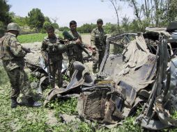 Oficiales de seguridad afganos contemplan un vehículo tras ser alcanzado por la explosión de una bomba. EFE  /