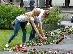 Una pareja deposita flores en Oslo en recuerdo de los fallecidos en los atentados en Noruega cometidos hace un año. AP  /