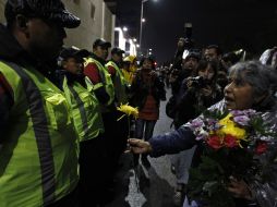 Una de las participantes en la marcha obsequia flores a los policías que realizan el cerco. REUTERS  /