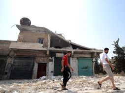 Dos hombres caminan frente a un edificio destruido tras un bombardeo. EFE  /