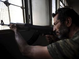 Un rebelde sirio apuntando su arma al exterior desde una escuela en Aleppo. EFE  /