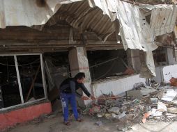 Un hombre limpia los escombros dejados por la explosión de un coche bomba. AFP  /