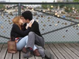 Enamorados se besan en el Pont des Arts, como transfondo, decenas de candados. ESPECIAL  /